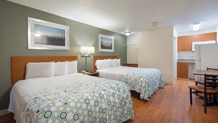 Interior photo of a double queen bed extended stay hotel with kitchenette and dining area