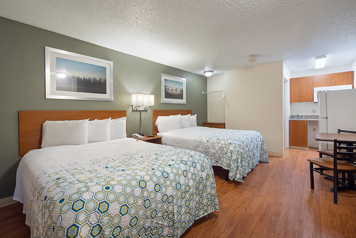 Interior photo of a double queen bed extended stay hotel with kitchenette and dining area