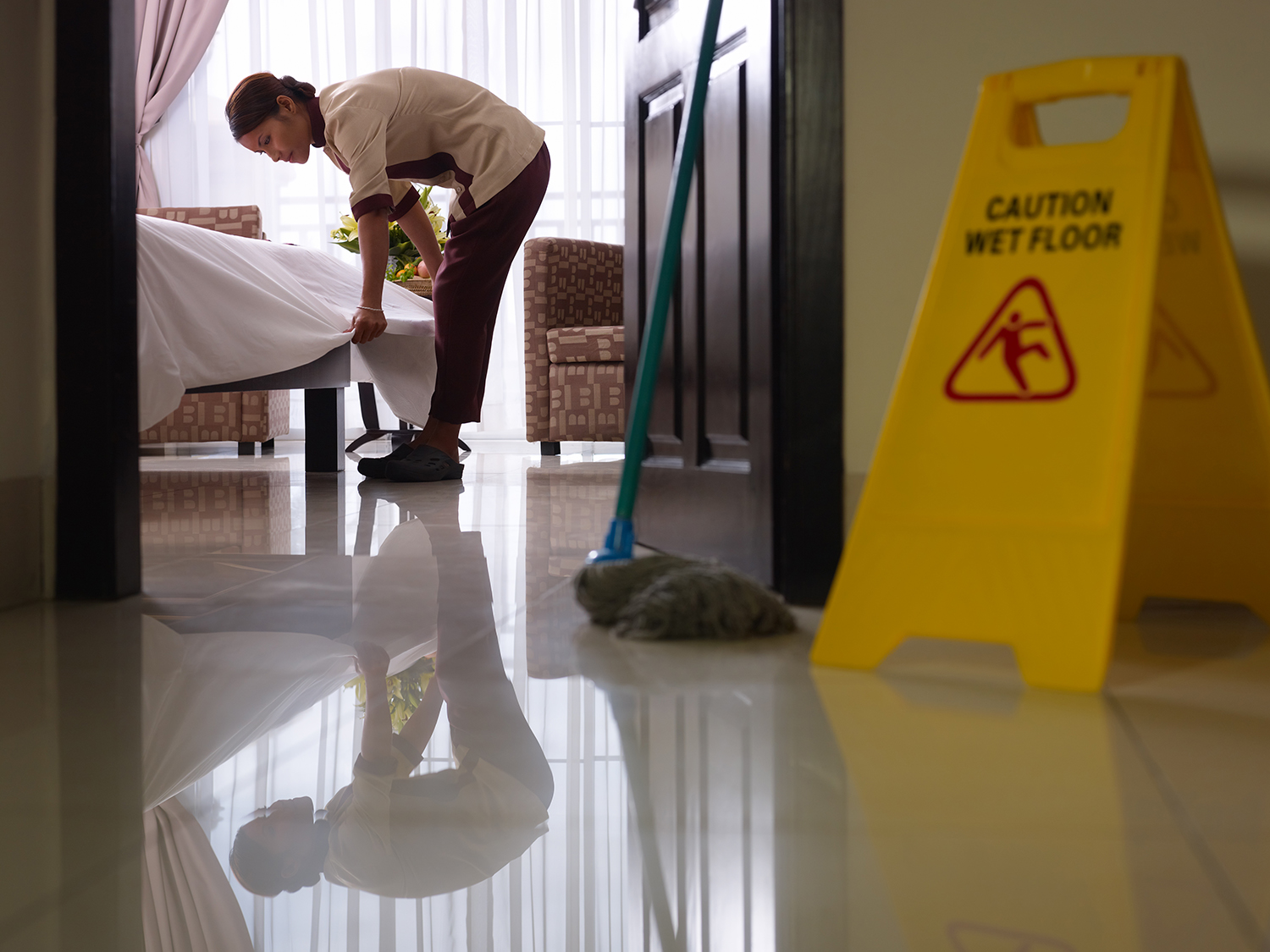 Maid at work and cleaning in an extended stay hotel room