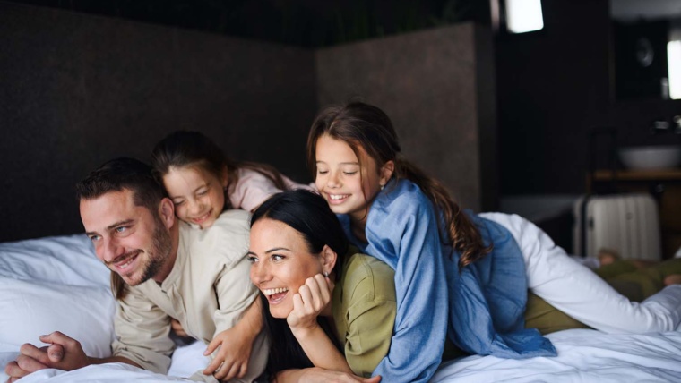 extended stay jobs happy young family with two children lying on bed in a hotel room
