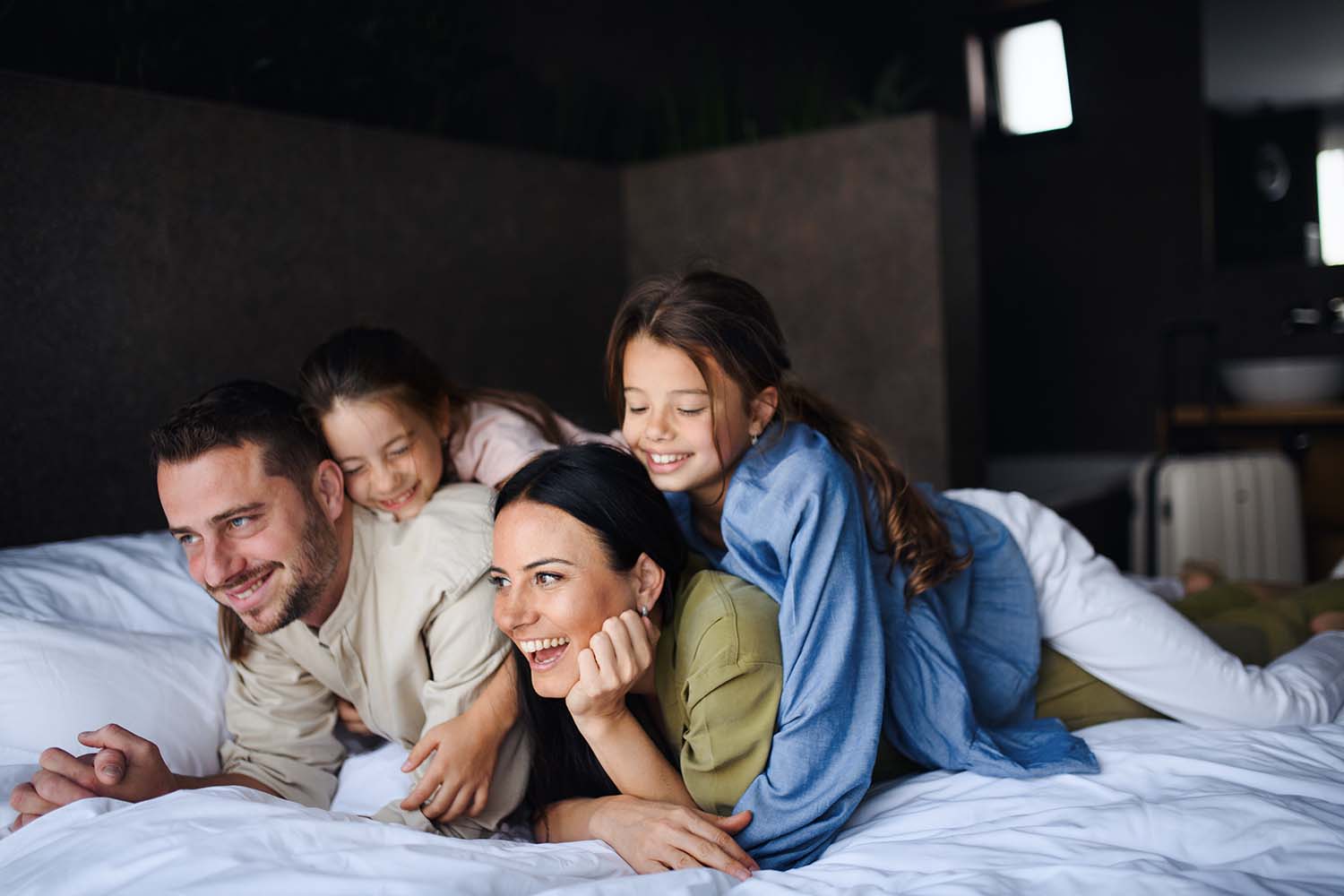 extended stay jobs happy young family with two children lying on bed in a hotel room